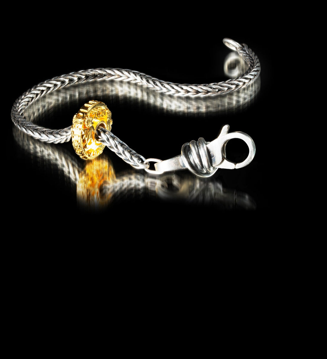 Silver bracelet with a gold charm on a black background